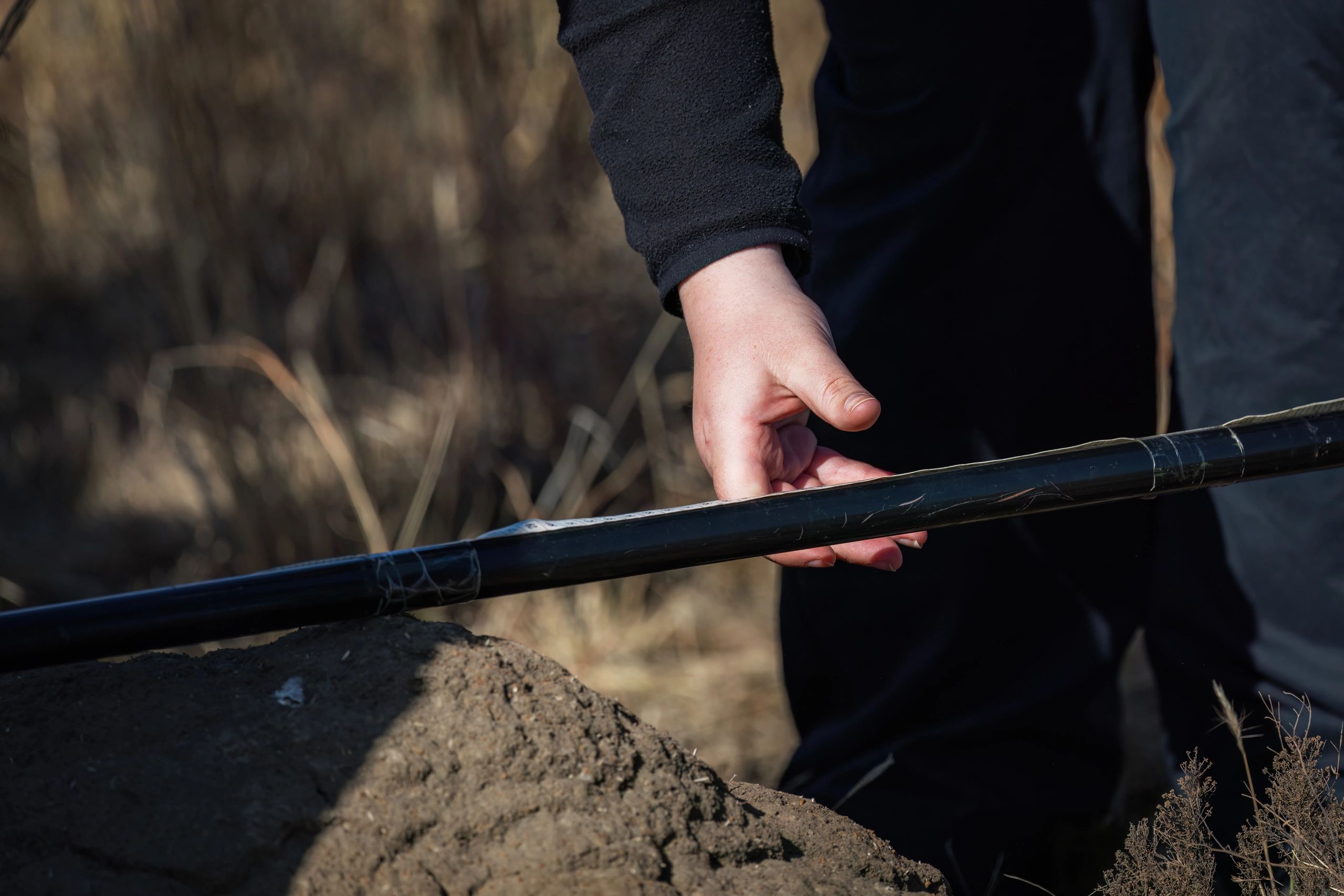 Field technician working on farm equipment in dry agricultural terrain